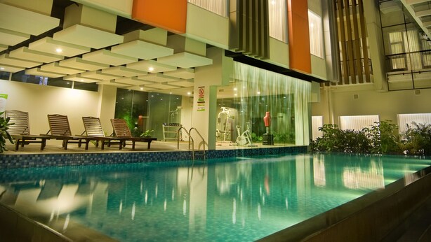 An indoor swimming pool with a modern architectural design, including a glass ceiling and tiered seating areas.