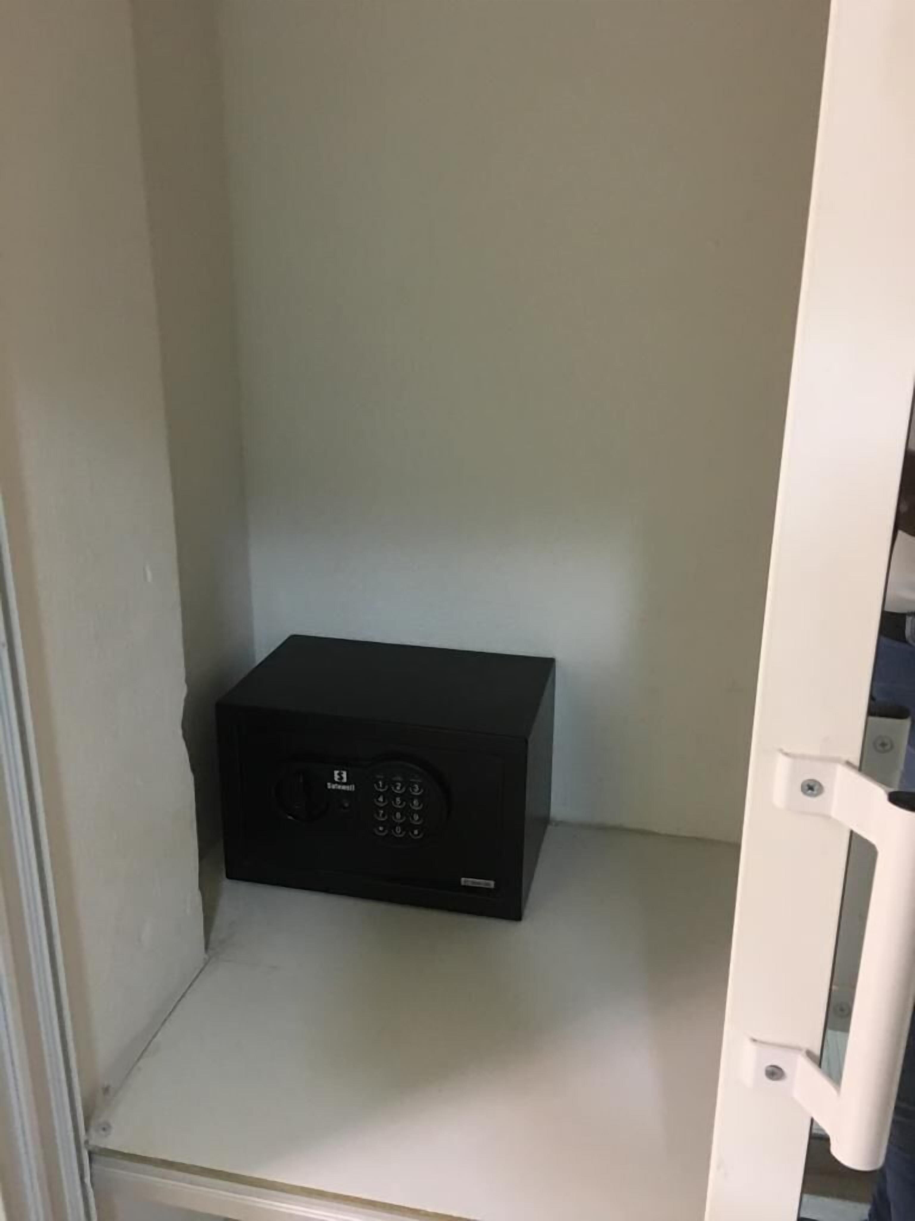 A black electronic device on a white shelf in a room with white walls.