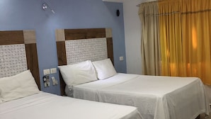 A hotel room with two single beds, a ceiling light, a wall-mounted phone, and a window with curtains. - Hotel Restaurant Hamilton (Boca Chica)