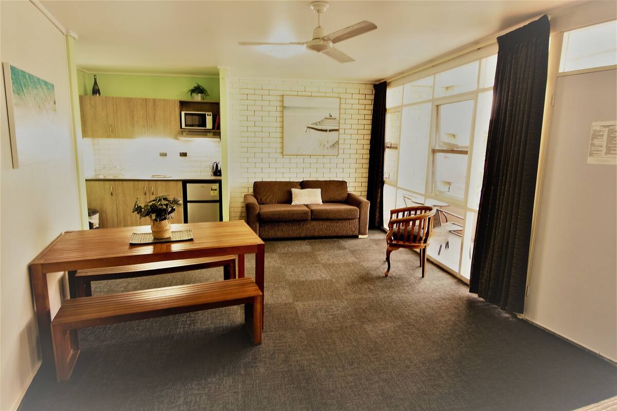 A compact living space with a kitchenette, a sofa, a dining table, and a chair.