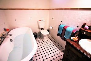 A bathroom with a bathtub, toilet, sink, and a tiled floor.