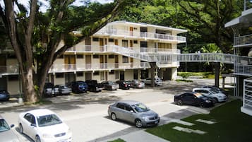 Un hotel de varios pisos con estacionamiento, rodeado de árboles y follaje.