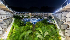 A hotel with a central swimming pool surrounded by lush greenery and multiple balconies. - Hotel Arenas en Punta Leona (Tárcoles)