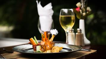 Ein Teller mit Essen, ein Glas Weißwein und Salz- und Pfefferstreuer auf einem Tisch.