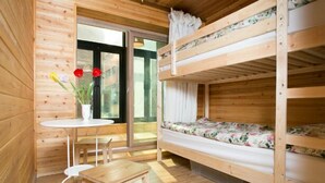 Une cabane en bois avec des lits superposés, une petite table et une fenêtre avec des rideaux.