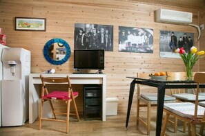 A compact kitchen with a dining area, a refrigerator, a sink, and a television.