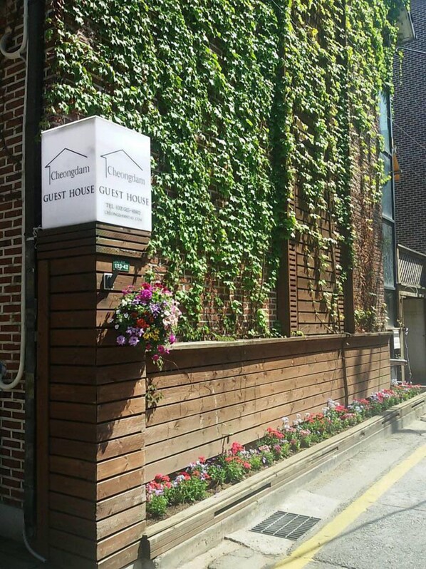 A guest house with a brick facade and a sign indicating its name.