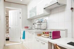 A modern kitchen with white cabinets, a countertop, a toaster, and a pink laptop.