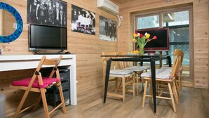 Un intérieur en bois comprenant une table à manger, des chaises, un téléviseur et des tableaux encadrés accrochés au mur.