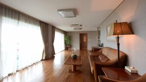 Una habitación amplia con piso de madera, un sofá, una mesa y una lámpara.