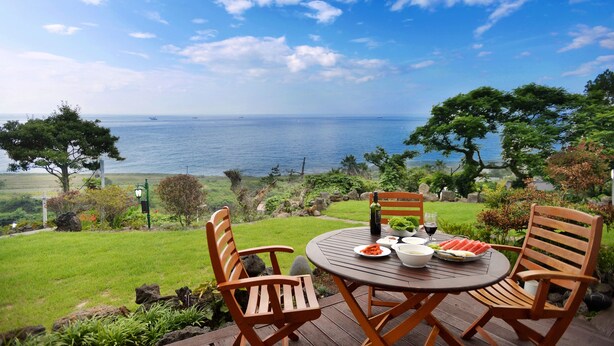 Una mesa de madera redonda con cuatro sillas, ubicada en una terraza con vista al mar.