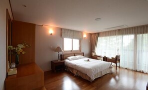 Ein modernes Hotelzimmer mit einem großen Bett, Nachttischen, einem Schreibtisch und einem Sessel.