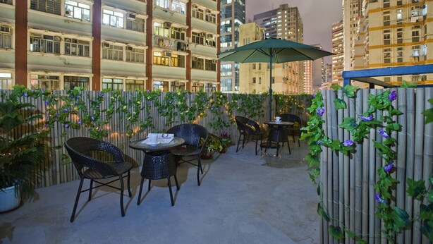 An outdoor patio area with bamboo fencing, potted plants, and wicker chairs and tables. - Mingle Place With The Star (Hong Kong)