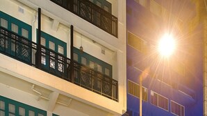 A multi-story building with a restaurant on the ground floor, balconies with black railings, and a bright street lamp in the foreground. - Mingle Place With The Star (Hong Kong)