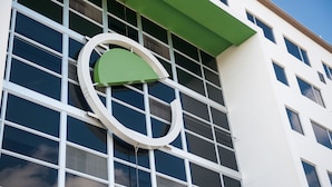 Un edificio moderno con un llamativo logo verde y blanco en la fachada.