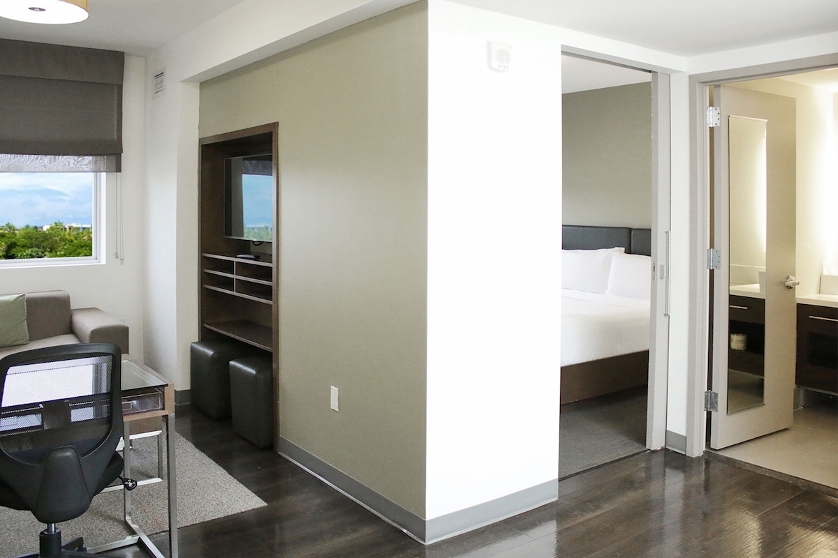Une chambre d’hôtel moderne équipée d’un lit, d’un bureau, d’une chaise et d’un téléviseur.