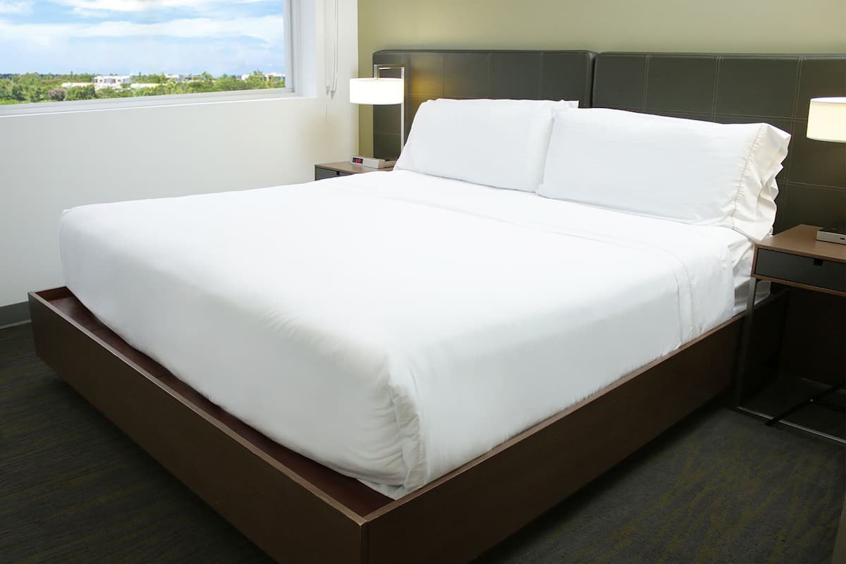 Una cama bien hecha con sábanas blancas en una habitación de hotel.