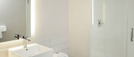A modern bathroom with a white sink, a toilet, and a glass-enclosed shower.