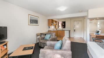 A modern hotel room with a living area, kitchenette, and a separate bedroom.