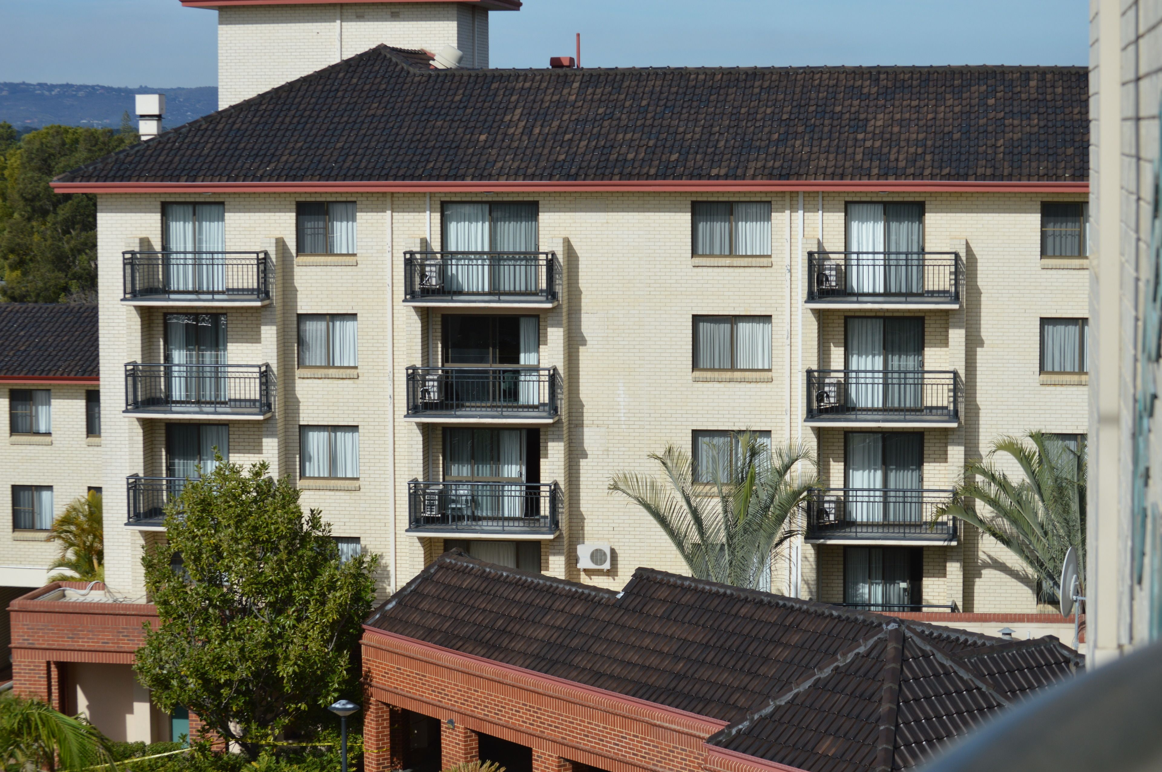 A multi-story building with balconies, air conditioning units, and a tiled roof.
