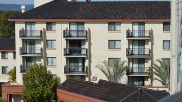 A multi-story building with balconies, air conditioning units, and a tiled roof.
