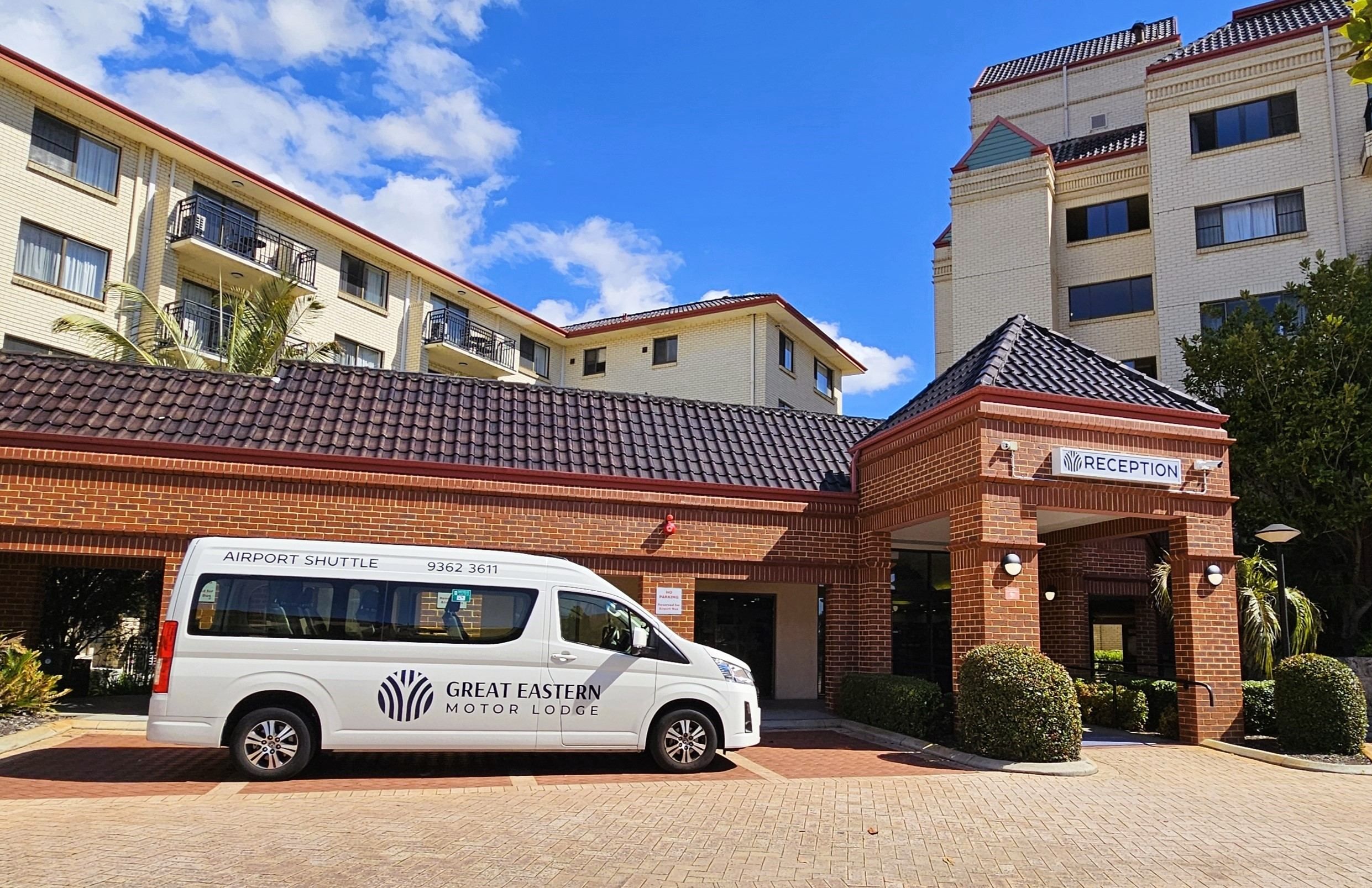 A white shuttle bus parked in front of a building with a reception area.