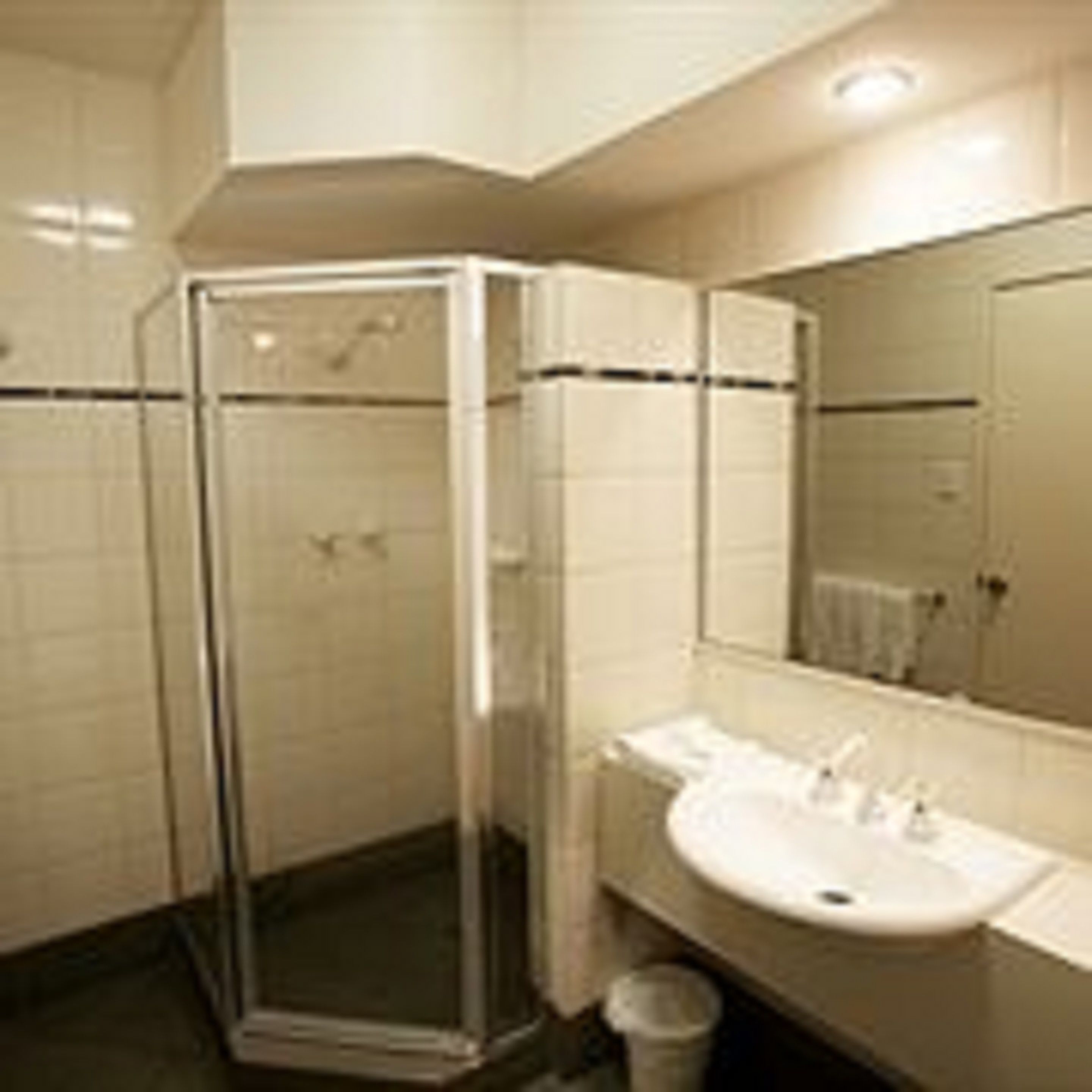 Un baño moderno con cabina de ducha de vidrio, lavabo con espejo y paredes con azulejos.