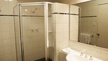 Un baño moderno con cabina de ducha de vidrio, lavabo con espejo y paredes con azulejos.