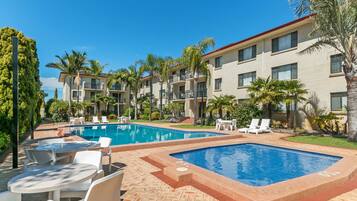 Een buitenzwembad, ligstoelen bij het zwembad