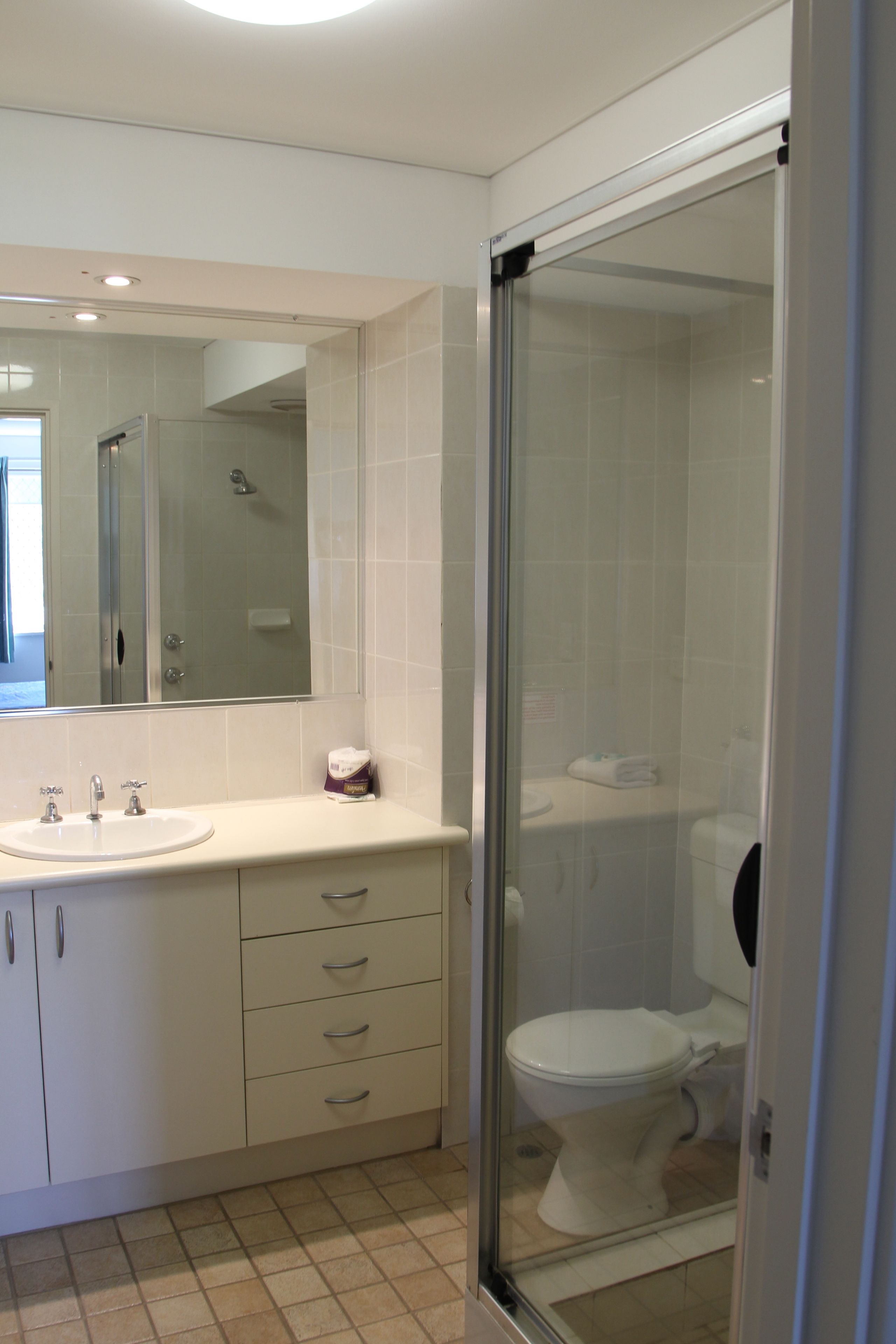 A modern bathroom with a glass-enclosed shower, a white sink, and a toilet.