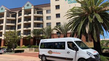 A white shuttle bus parked in front of a building with a sign reading "Great Eastern Motor Lodge".