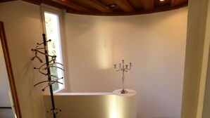 A corner bathroom with a white bathtub, a mirror, and a candelabra.