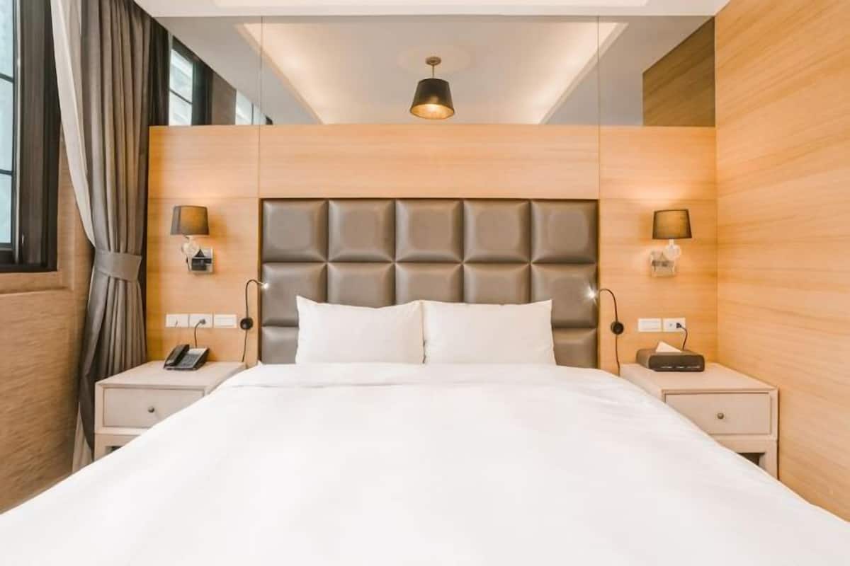 Ein Hotelzimmer mit einem großen Bett, zwei Nachttischen, einer Kopfteil und einer Deckenleuchte.