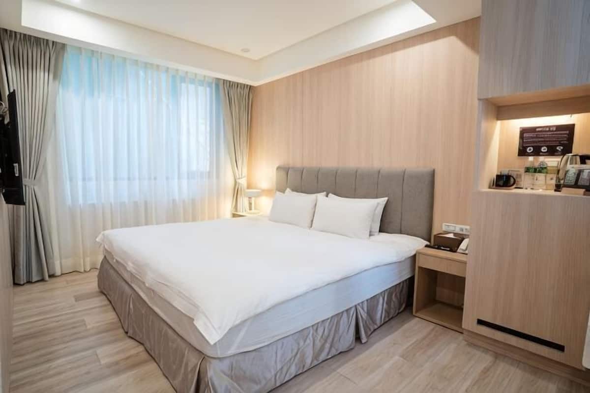 Ein Hotelzimmer mit einem großen Bett, einem Nachttisch, einer Lampe und einer integrierten Kaffeestation.