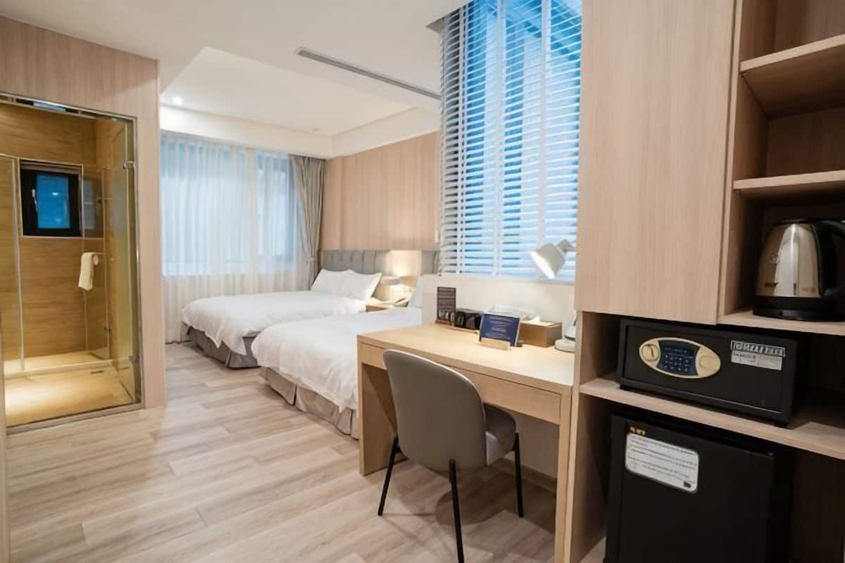 Ein Hotelzimmer mit Bett, Schreibtisch, Stuhl und einer Kaffeemaschine.