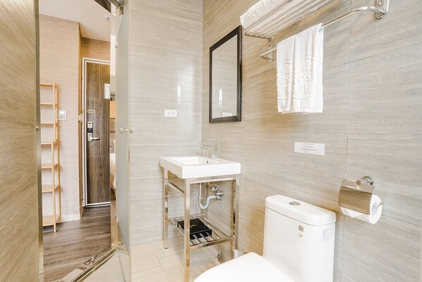 A modern bathroom with a glass shower enclosure, a white sink, and a toilet. - Royal Rose Hotel Ximen (Taipei)