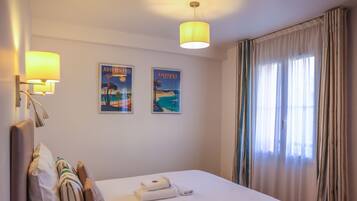 Una camera d'albergo con un letto, due lampade a parete e due poster incorniciati.