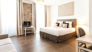 Quarto de hotel com cama, televisão, escrivaninha e cadeira.