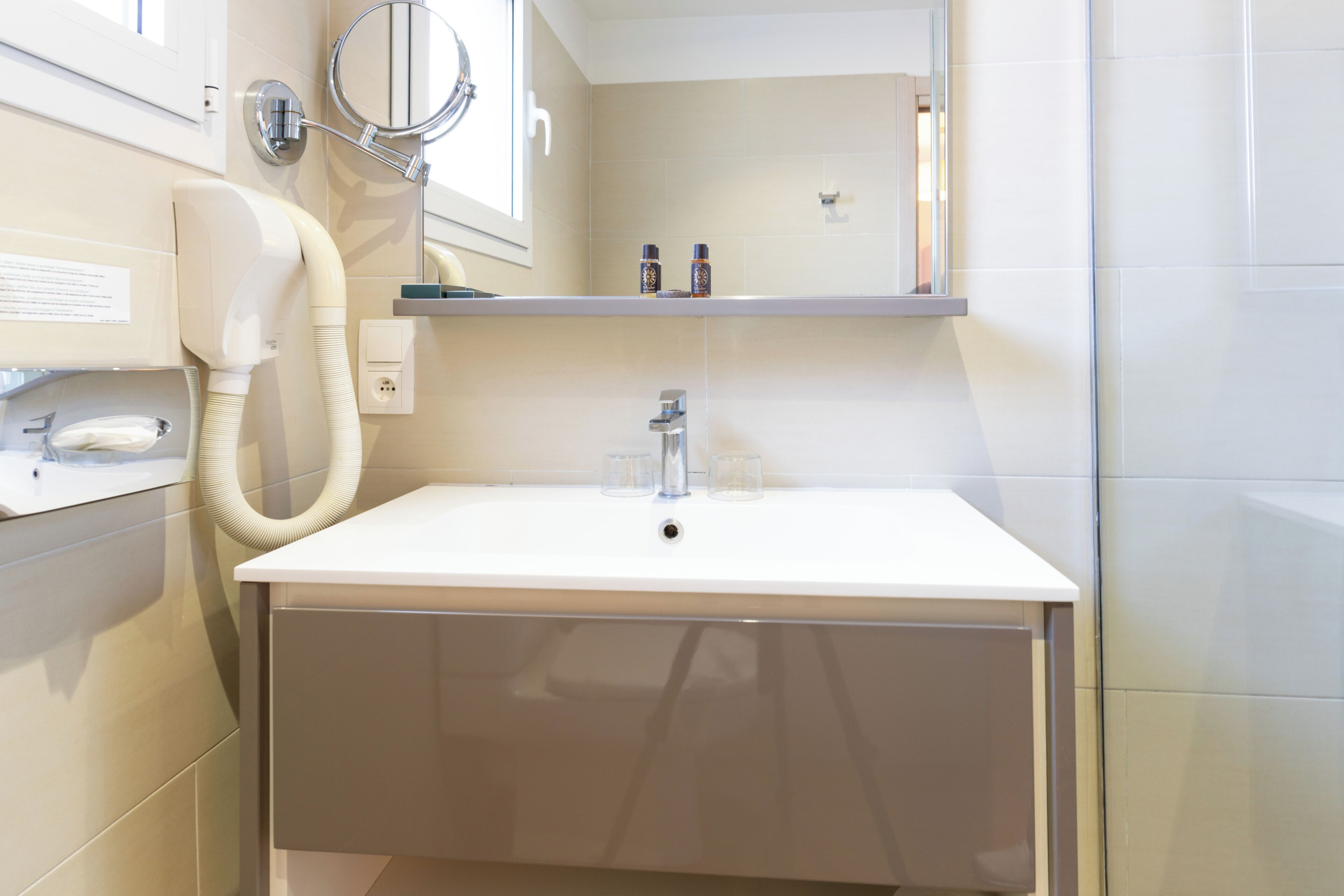 Un baño con un lavabo blanco, espejo y perchero para toallas.
