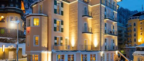 A multi-story hotel with balconies, a snow-covered landscape, and a night-time setting.