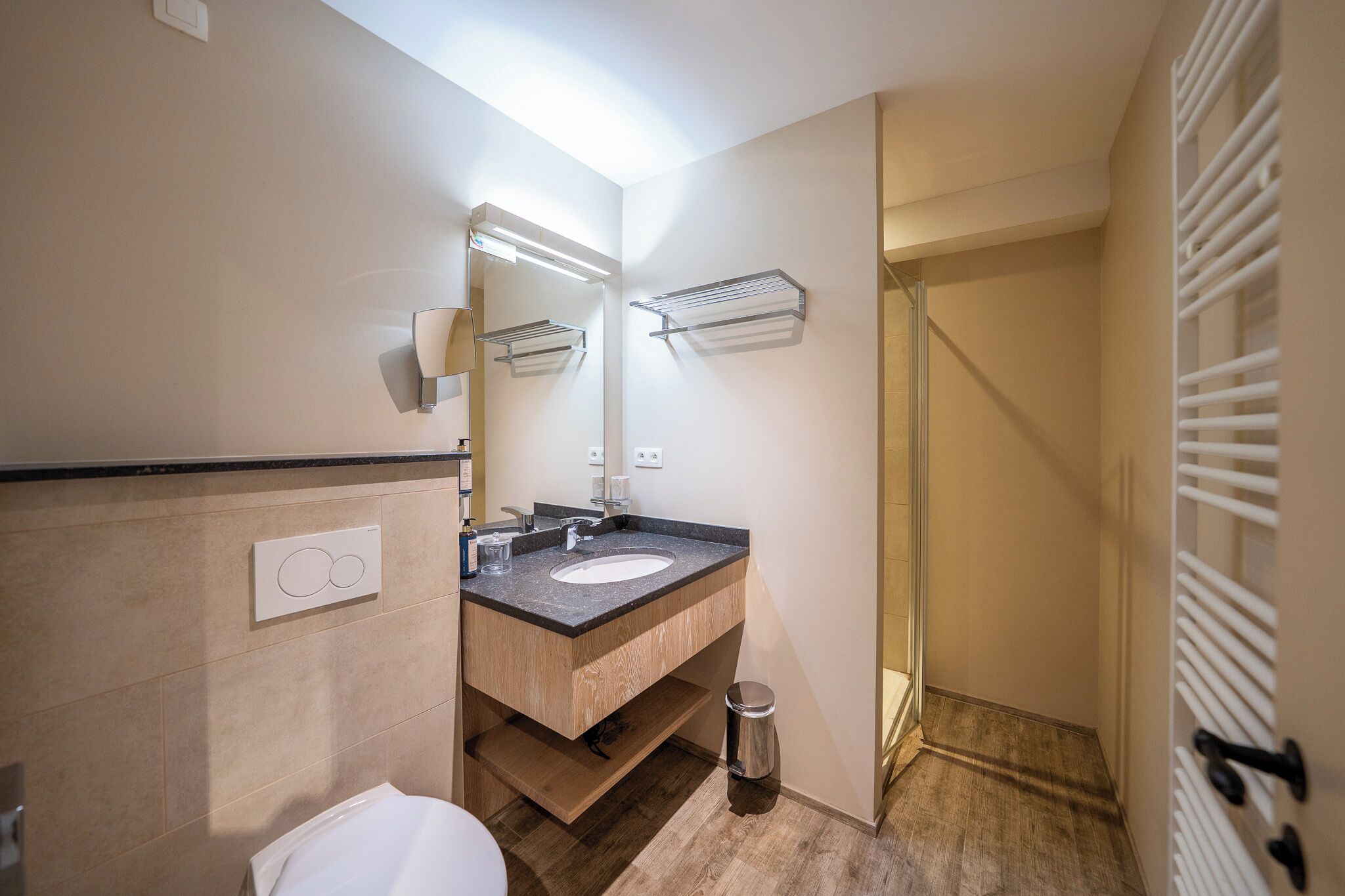 A modern bathroom with a sink, mirror, towel rack, and a shower area.