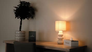 A desk with a potted plant, a lamp, a welcome sign, and a tissues box.