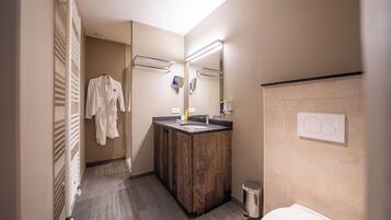 A modern bathroom with a wooden vanity, a mirror, a towel rack, and a toilet.
