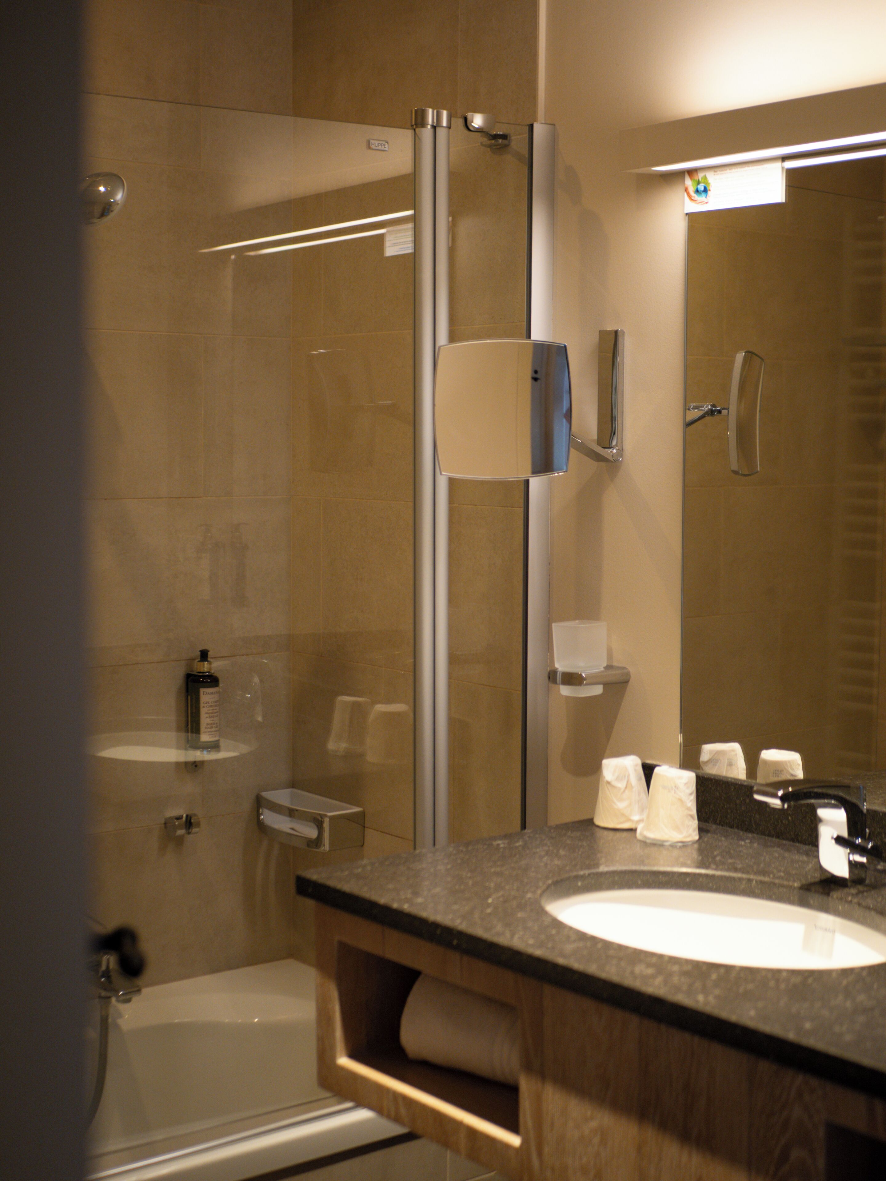 A bathroom with a glass shower enclosure, a sink with a mirror, and a toilet.
