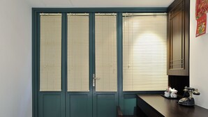 A room with a green door, a desk with a telephone, and a small table. - Mingle Place by The Park (Hong Kong)