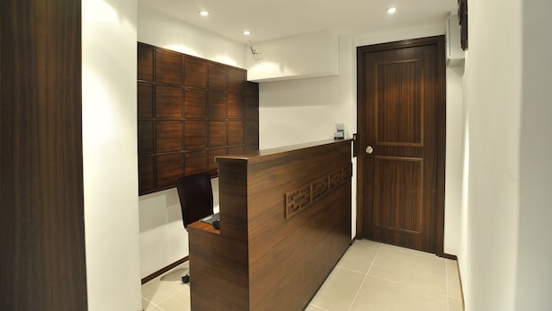 A reception area with a wooden reception desk, a wall-mounted panel, and a wooden door. - Mingle Place by The Park (Hong Kong)