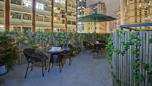 An outdoor patio area with bamboo fencing, potted plants, and wicker chairs and tables. - Mingle Place by The Park (Hong Kong)