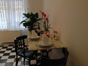 A dining table set with plates, cutlery, and a bottle of wine, surrounded by chairs.
