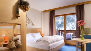Habitación de hotel con cama, escritorio con lámpara, silla, ventana con vista a árboles y un adorno en la pared.