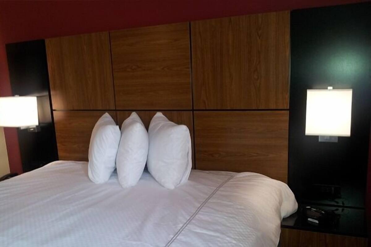 A hotel room with a large bed, wooden headboard, and two bedside lamps.